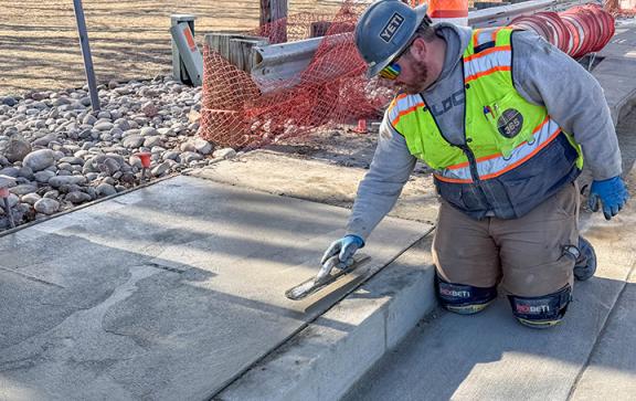 A man smooths a new concrete sidewalk.