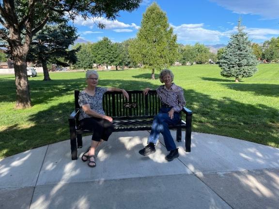 Two ladies sit on the Parkinson's Foundation Memorial Bench