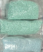 Seized M30 tablets in plastic bags. The tablets are round and come in differing shades of blue.