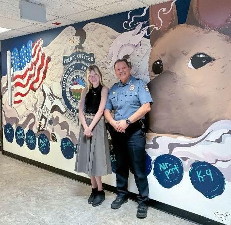 Emme Rayman and Chief Adrian Vasquez smile for a photo together in front of Rayman's mural.