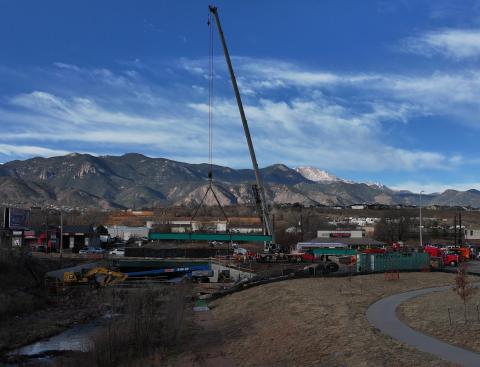 A crane positions a 64-foot-long steel I-beam girder at the 8th Street bridge over Fountain Creek on Dec. 17. Crews placed three girders that will support a new northbound traffic lane and multiuse sidewalk/trail across the creek.
