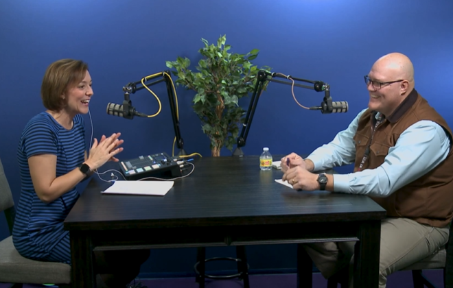 a woman and a man at a table talking into microphones