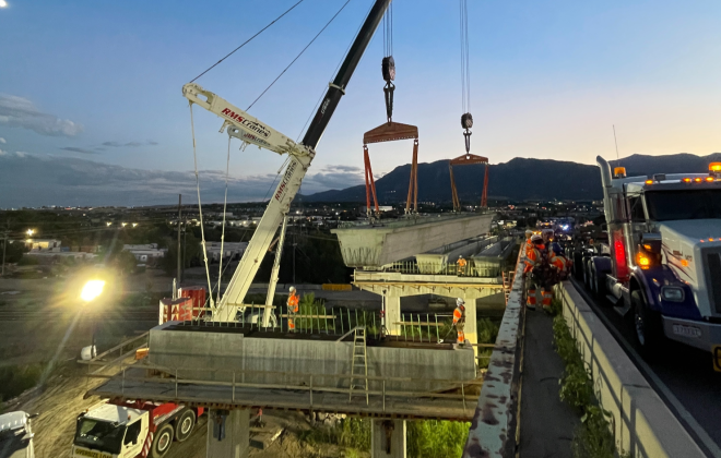 A crane places a large beam on Circle Bridge in the evening, as part of the Circle Bridges project.
