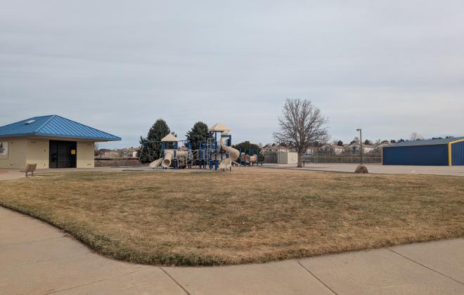 A bathroom and a playground are visible at Rampart Community Park on a winter day. 