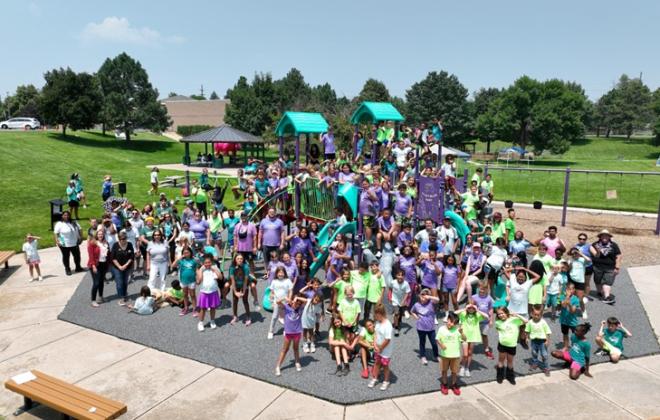Staff and participants of a summer camp take a group photo together on a park playground.
