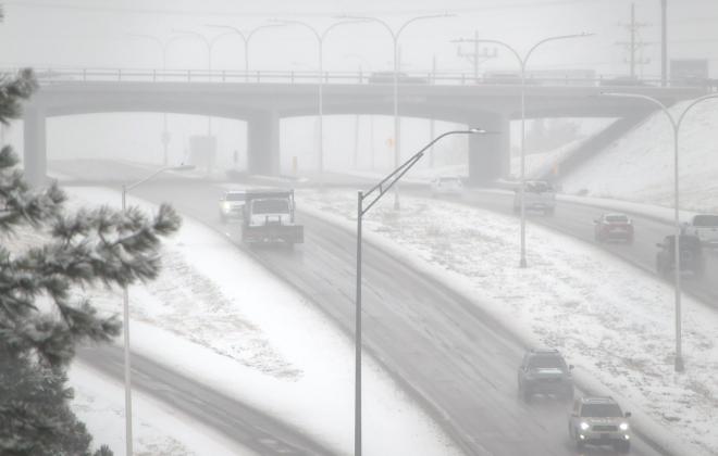 Cars drive on the road during a heavy snow storm.